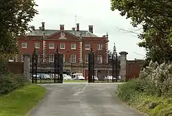 A large red brick building behind black iron gates.