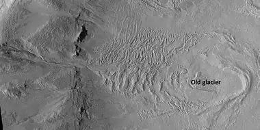 Glacier on a crater floor, as seen by HiRISE under HiWish program. The cracks in the glacier may be crevasses.  There is also a gully system on the crater wall.