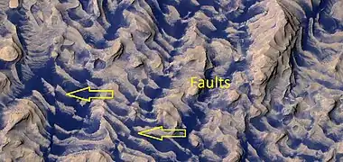 Close, color view of layers and dark dust on floor of Danielson Crater, as seen by HiRISE under HiWish program.  Faults are indicated with arrows.