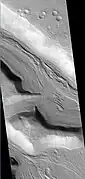 Hypsas Valles, as seen by HiRISE. Ridges are probably due to glacial flow.  So water ice is under a thin layer of rocks.