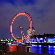 A ferris wheel blurs into a neon circle.