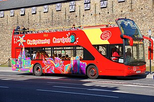 A red open-top bus bearing playful letteringː "City Sightseeing Caerdydd" bus